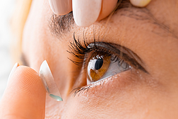 Close up woman applying contact eye lens.