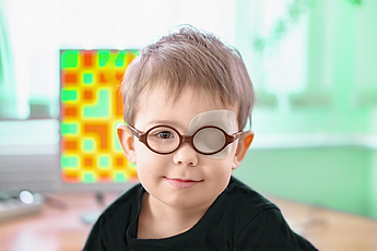 A little boy wearing glasses and an eye patch (plaster, occluder)